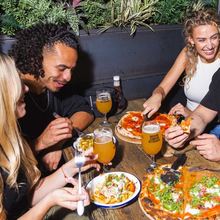 A group sharing food and pizza at a table at BrewDog Bangkok